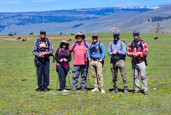 A group of hikers stand in a field at Yellowstone