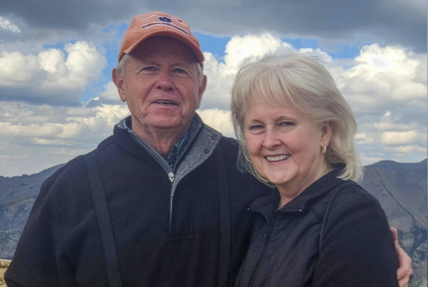 Man and woman standing outside posing for picture in front of mountains