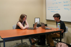 Katie Temple works at a table with students in the CFWE's Miller Writing Center branch